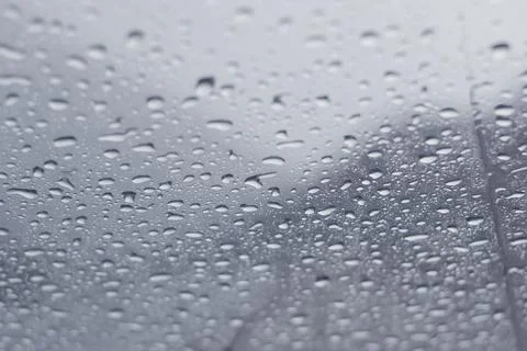 Raindrops dripping across a window in a cold winter day. Close up, texture ba Stock Photos