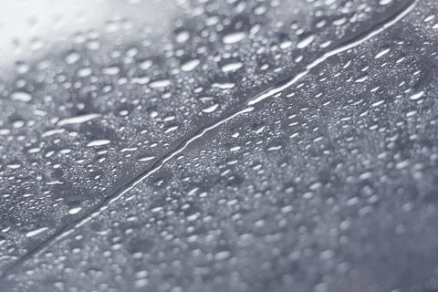 Raindrops dripping across a window in a cold winter day. Close up, texture ba Stock Photos