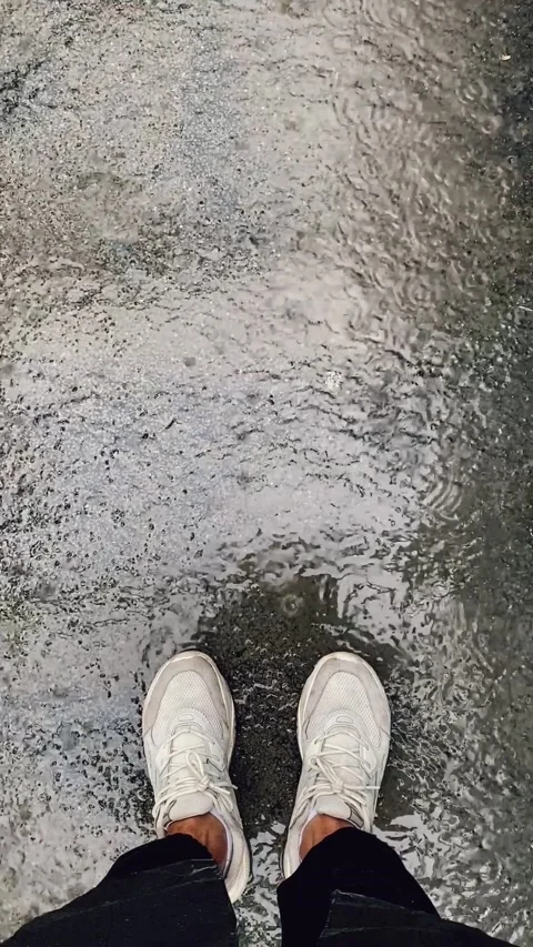 Raindrops fall on the asphalt. View of the legs. Vertical video Stock Footage 233603988