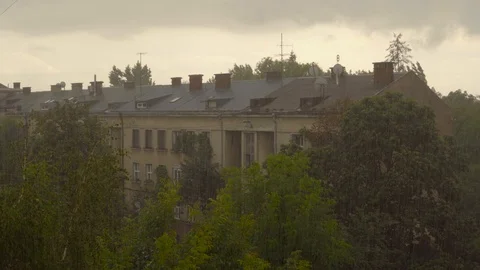 Raindrops fall on the background of the building and its roof and trees. Drops Stock Footage 92387390