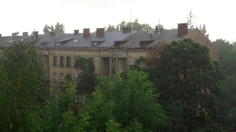 Raindrops fall on the background of the building and its roof and trees. Drops Stock Footage 92390356