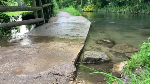 Raindrops fall on footpath puddle and river Stock Footage 275668498