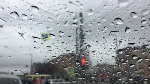 Raindrops fall on the glass of the car. The car stands and waits at a traffic Stock Footage 154027936