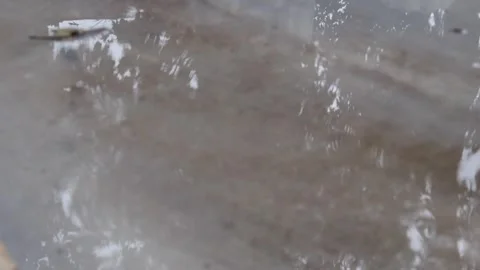 Raindrops fall in a gray puddle on the asphalt Stock Footage 284456861