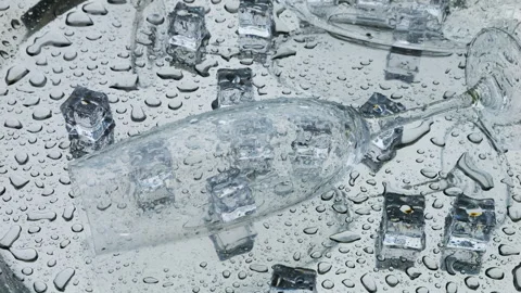 Raindrops fall on ice cubes and glass wine glasses lying on silver metal salver. Stock Footage 313367564