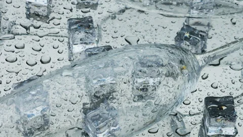 Raindrops fall on ice cubes and glass wine glasses lying on a silver metal. Vídeo Stock 313907038