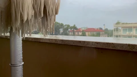 Raindrops fall on the parapet and folded parasol on the balcony. Slow 動画素材 164526901