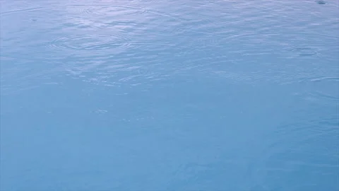 Raindrops fall on surface of  pool, forming circles and bubbles. Abstract Stock Footage 141379060