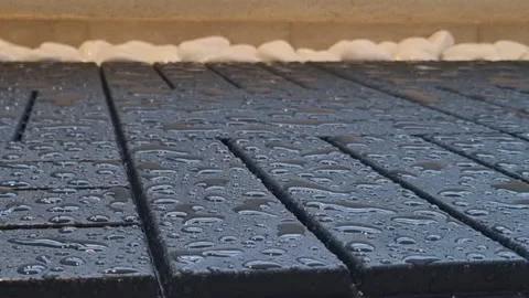 Raindrops fall on the wet black decking floor and white ceramic stones 動画素材 196994074
