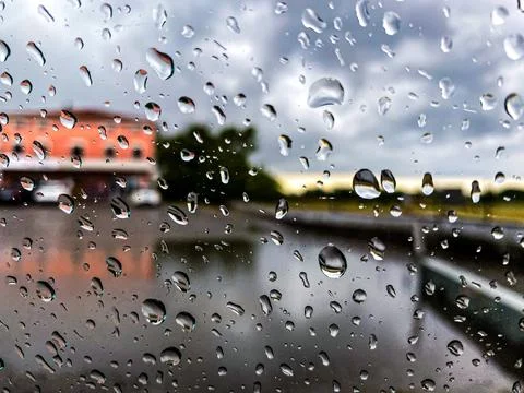 Raindrops fall on a window with a boat in the distant background Stock Photos