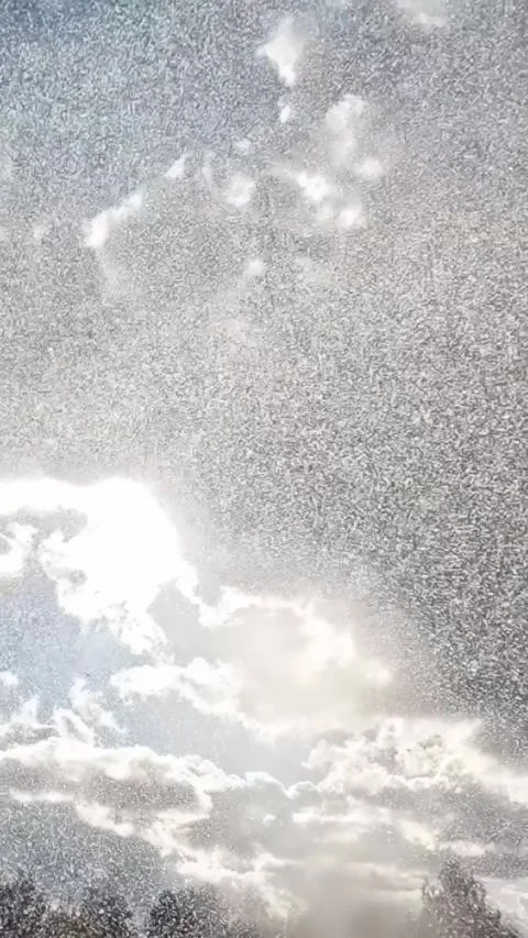 Raindrops falling against cloudy sky with sunlight streaming through clouds Stock Footage 316571490