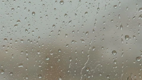 Raindrops falling and sliding down window glass during rainy day in close up Stock Footage 334837110