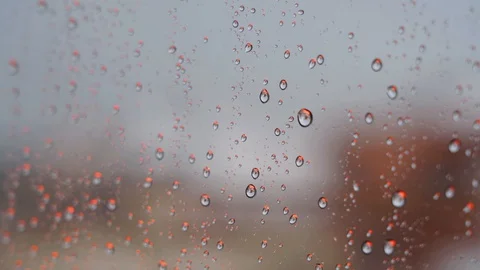 Raindrops falling and stuck with an orange light from a window while it's rai Video stock 129043571