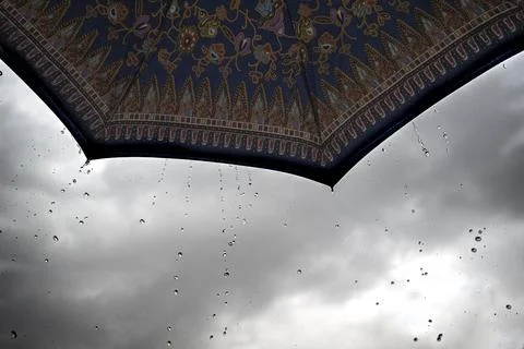 Raindrops falling from a batik print umbrella Stock Photos