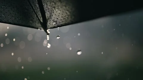 Raindrops falling from a black umbrella captured in cinematic, moody lighting Stock Footage 309961905
