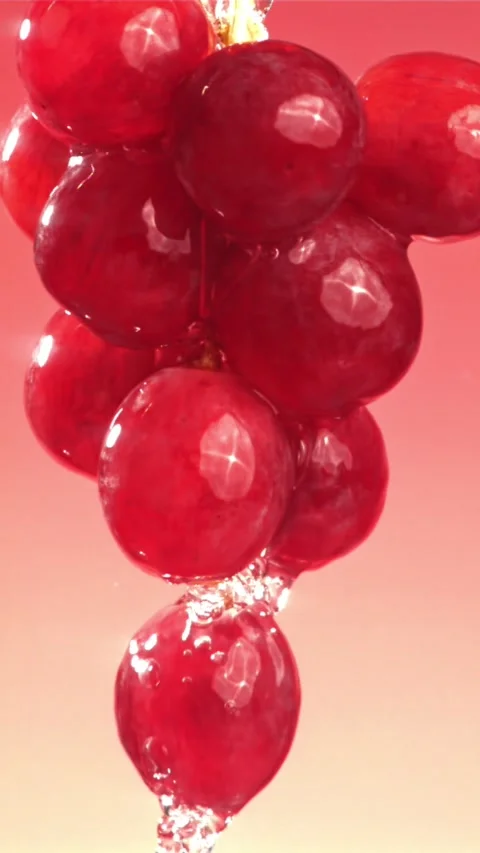Raindrops falling on a branch of red grapes on a pink background. Filmed on a Stock Footage 335314907