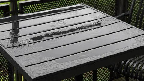 Raindrops falling on a dark metal garden table on a rainy balcony Vidéo 343547705