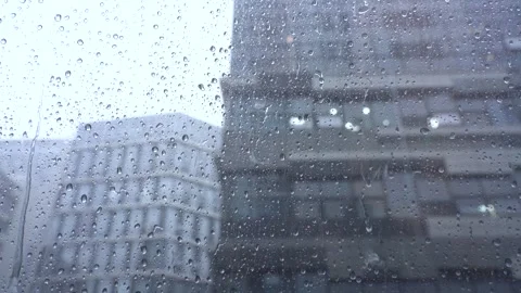 Raindrops Falling Down on Window Glass Overlooking a Gray Cityscape on Rainy Day Stock Footage 341957152