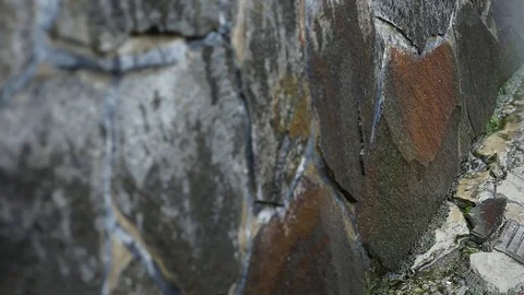 Raindrops falling during a thunderstorm against a stone wall, slow motion Stock Footage