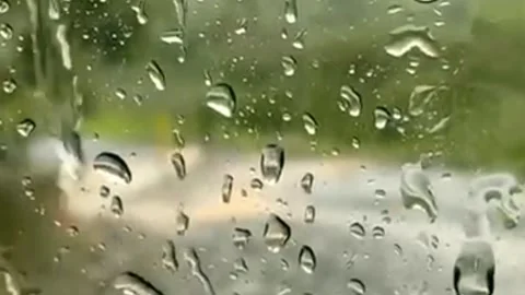 Raindrops falling on glass on blurry background Stock Footage 258732024