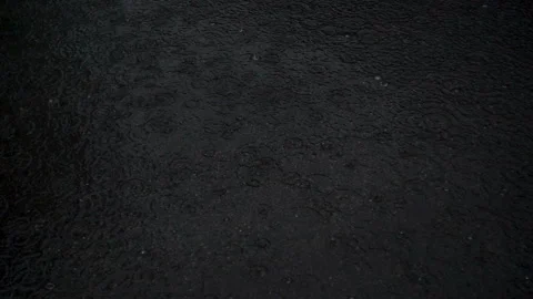 Raindrops falling in a large dark puddle as a background. Stock Footage 120514748