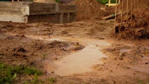 Raindrops falling into a muddy puddle at a construction site Stock Footage 341294400
