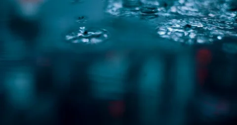 Raindrops falling into puddle at night. Rainy evening in street Stock Footage 127316982