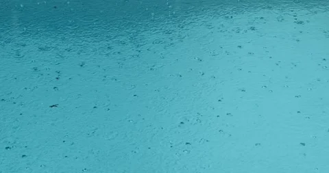 Raindrops falling into puddle water surface in slow motion. Close up of raining Stock Footage 243422721