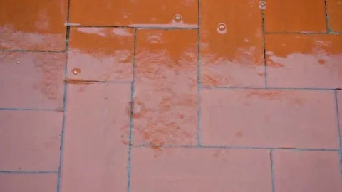 Raindrops falling red floor splashes heavy rain with water stream and bubbles Video stock 69242716