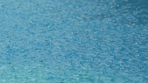 Raindrops falling in slow motion on a blue swimming pool surface Stock Footage 313813096