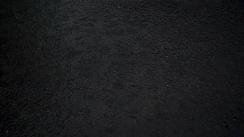 Raindrops falling in slow motion in a dark puddle Stock Footage 123103294