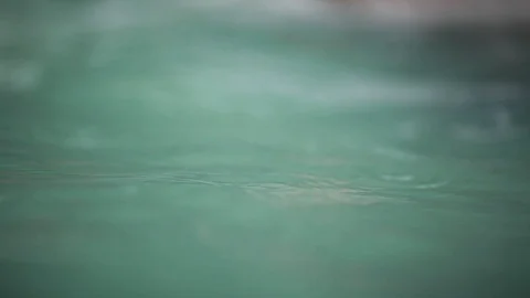 Raindrops falling on the surface of a blue pool, close up Stock Footage 104467465
