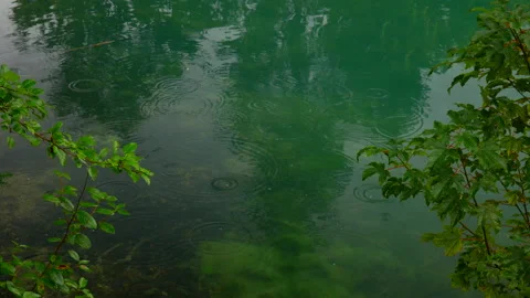Raindrops falling on water surface of natural Walchensee Lake during cloudy day Video stock 139606393