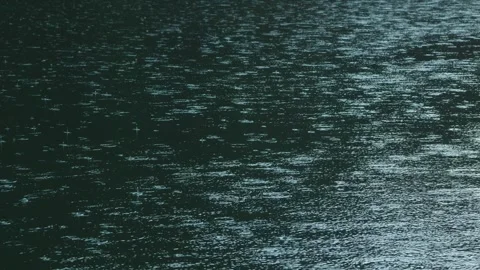 Raindrops falling on water surface - natural weather scene Видео 332060194