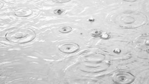 Raindrops falling onto the water surface, ripples, splashes, and bubbles 動画素材 343408788
