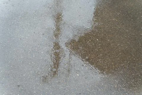 Raindrops falling on a wet asphalt surface creating ripples and reflections Stock Photos