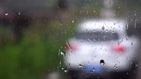 Raindrops Falling on Window Glass with Blurred Car in Background Stock Footage 342250302