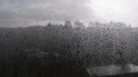 Raindrops falling on a window with an unfocused background of a mountain Stock Footage