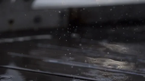 Raindrops falling on wooden deck Bright flashes of light reflected in puddle Video stock 96117560