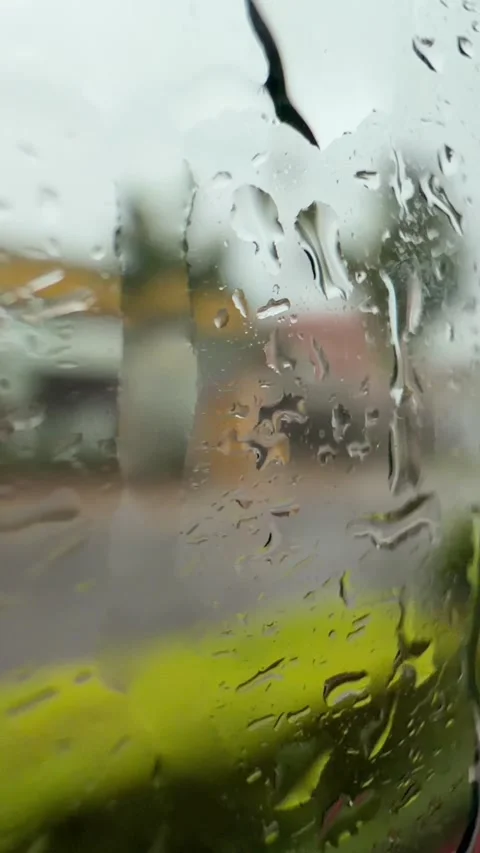 Raindrops flow down a bus window with a road and roadside objects visible outsid 스톡 동영상 340890392