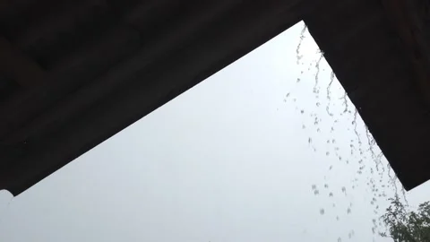 Raindrops Flow Down From the Triangular Roof during rain and gray sky Stock Footage 149872997