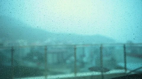 Raindrops Flowing Down Glass Window with Blurred Cityscape in Background Stock Footage 344346505