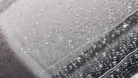 Raindrops flowing down the surface of a car windshield, close-up view from Stock Footage 274047965
