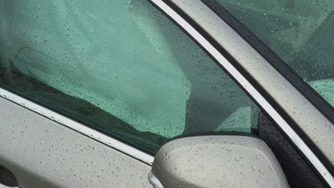 Raindrops gently cascading on a car window while observing the airbag deployment Stock Footage 315227484