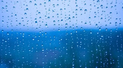 Raindrops on the glass close-up. Background texture. Bad weather. Blue cold s Stock Photos