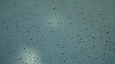 Raindrops on Glass Surface with Blurred Blue Background on a Wet Day Stock Footage 343245936