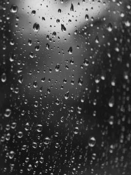 Raindrops on glass surface forming abstract monochrome pattern with soft focu Stock Photos