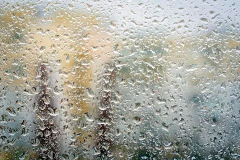 Raindrops on glass, window background view of buildings out of focus. Stock Photos