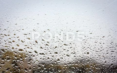 Raindrops on glass, window background view of buildings out of focus. Stock Photos