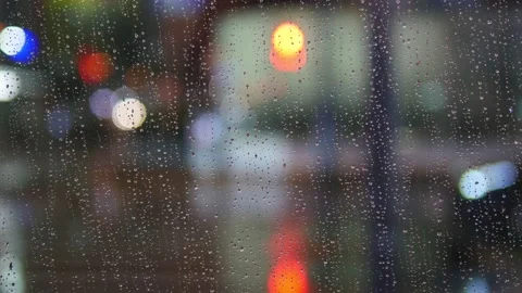 Raindrops on the glass window, through city lights and passing car lights Stock Footage 239995998